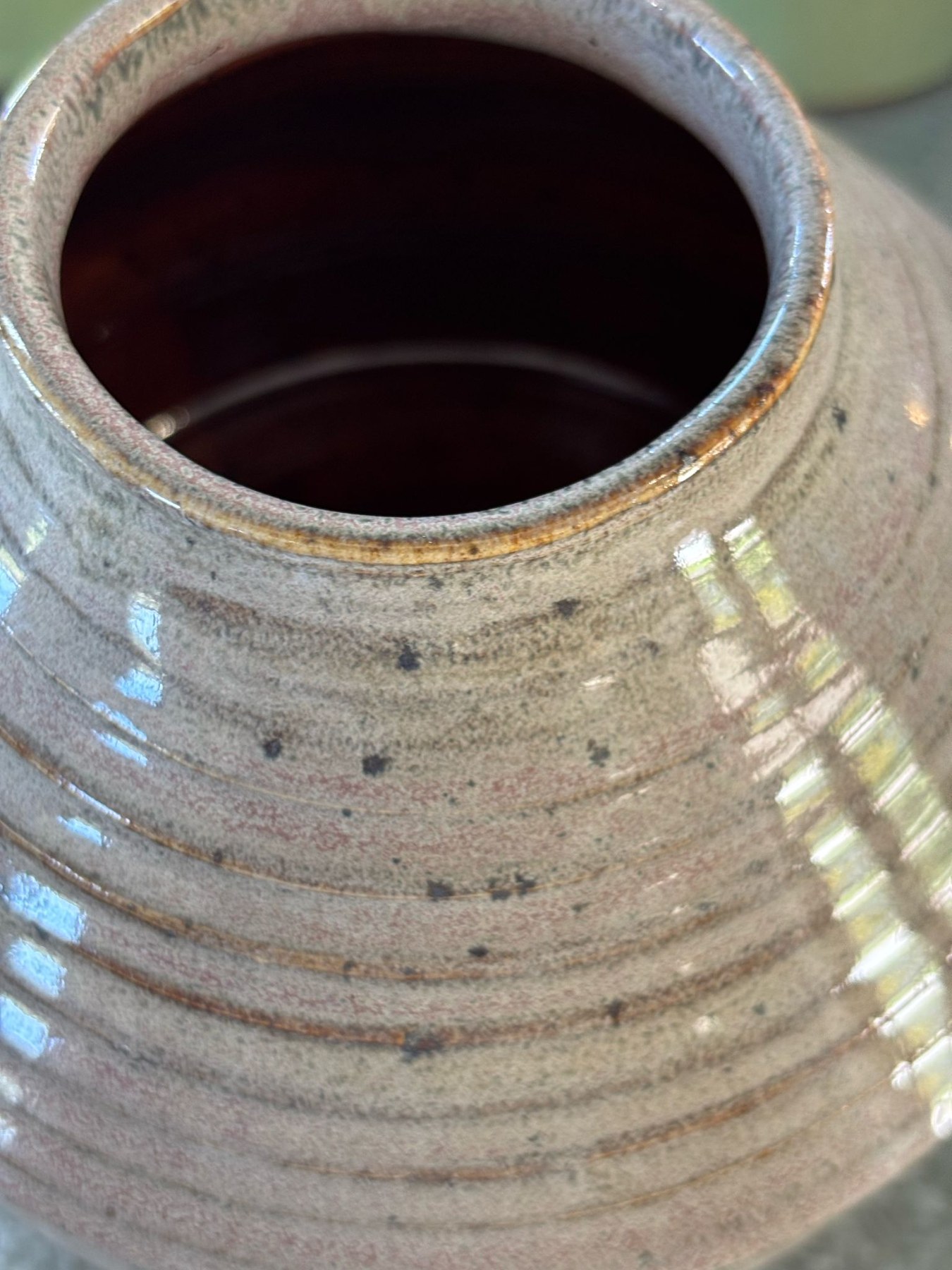Close view of a glazed vessel rim, dark interior and horizontal turning lines